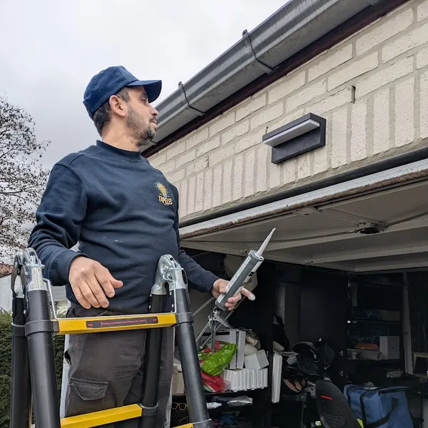 Électricien Tapelec posant une applique extérieure au-dessus d'une porte de garage