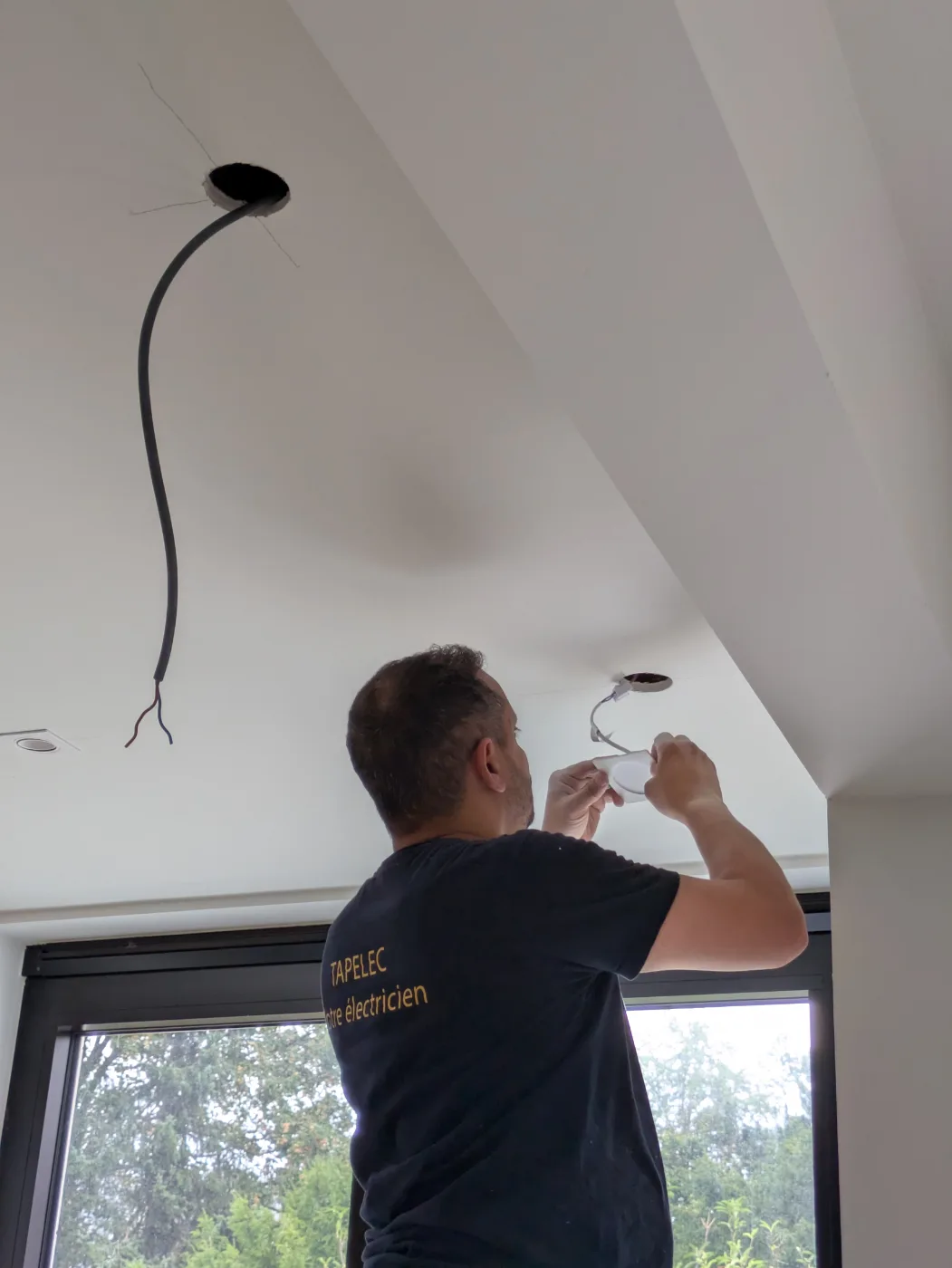 Électricien Tapelec raccordant un spot LED au plafond d'une cuisine
